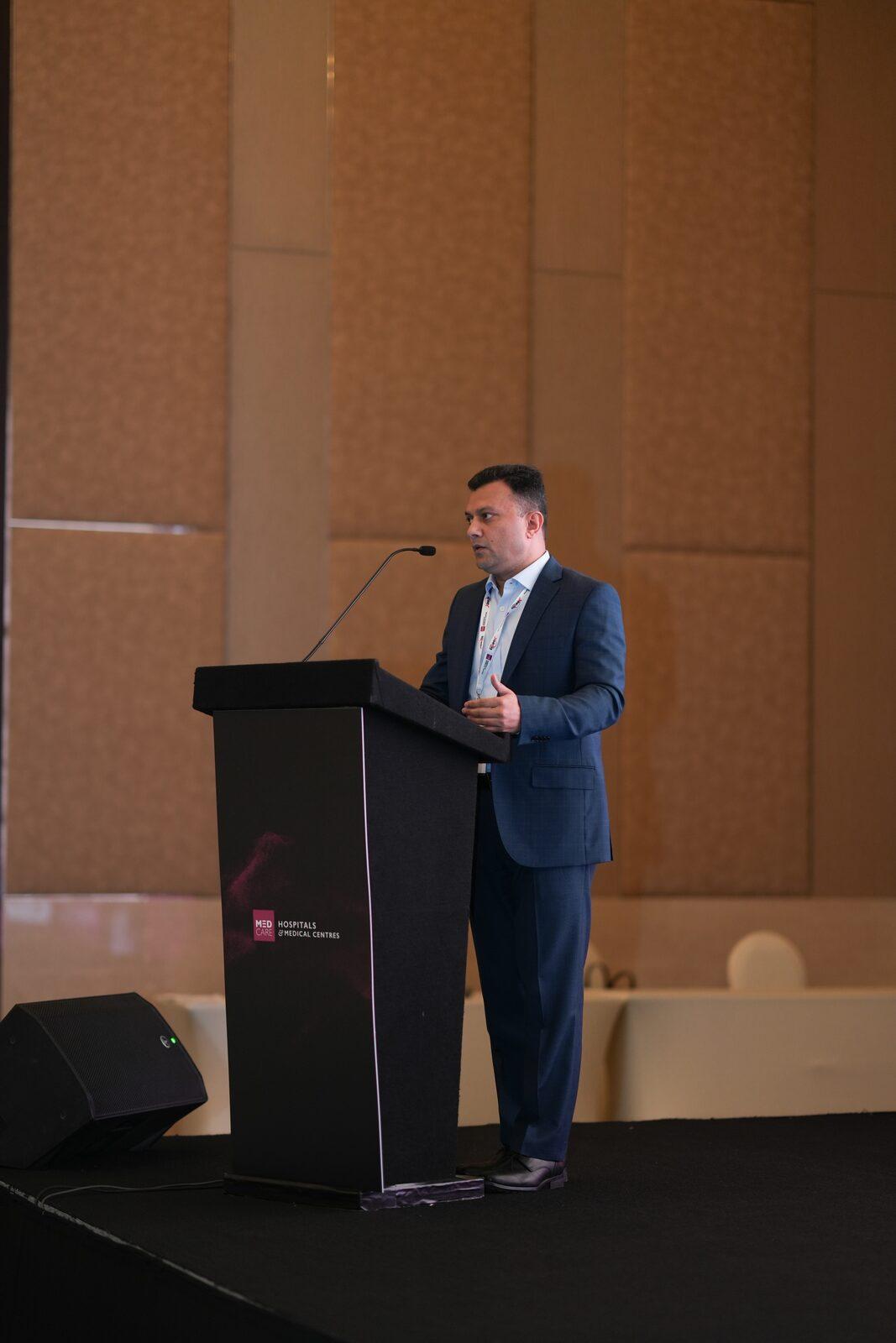 Dr. Vinod Hegade at the IMPACT 2026 podium, Medcare Hospitals & Medical Centres